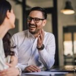 meddic sales: A man laughs and gestures while talking with a woman.