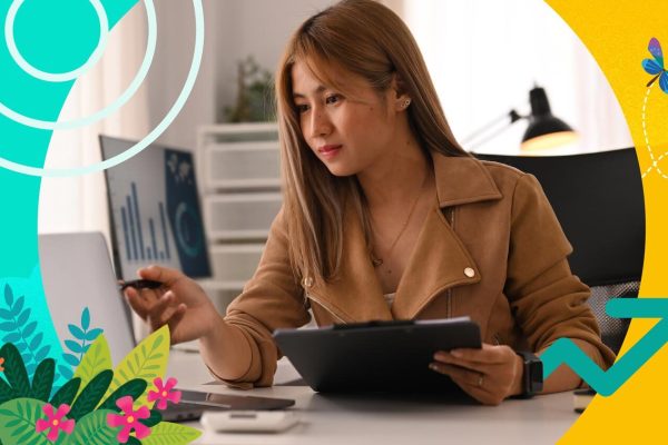 Sales person sitting at a desk and working on a computer. She is looking at spreadsheets that show competitive pricing strategies.