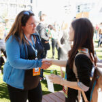 An image of Dreamforce, an annual event for small business owners, where two women meet and shake hands.