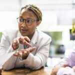 Businesswoman, professionally dressed, sitting at a table and leading a meeting in an office / marketing quotes