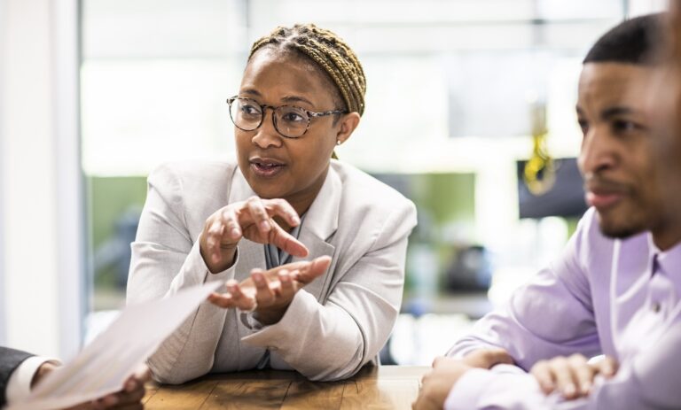 Businesswoman, professionally dressed, sitting at a table and leading a meeting in an office / marketing quotes