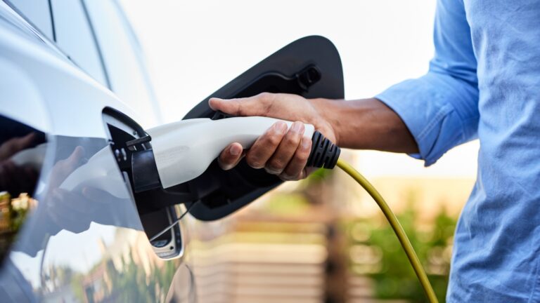 Man plugging in cable while charging electric car