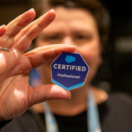 Close-up of a 'Salesforce Certified Professional' badge sticker held in a hand, representing the new AI certification in the portfolio