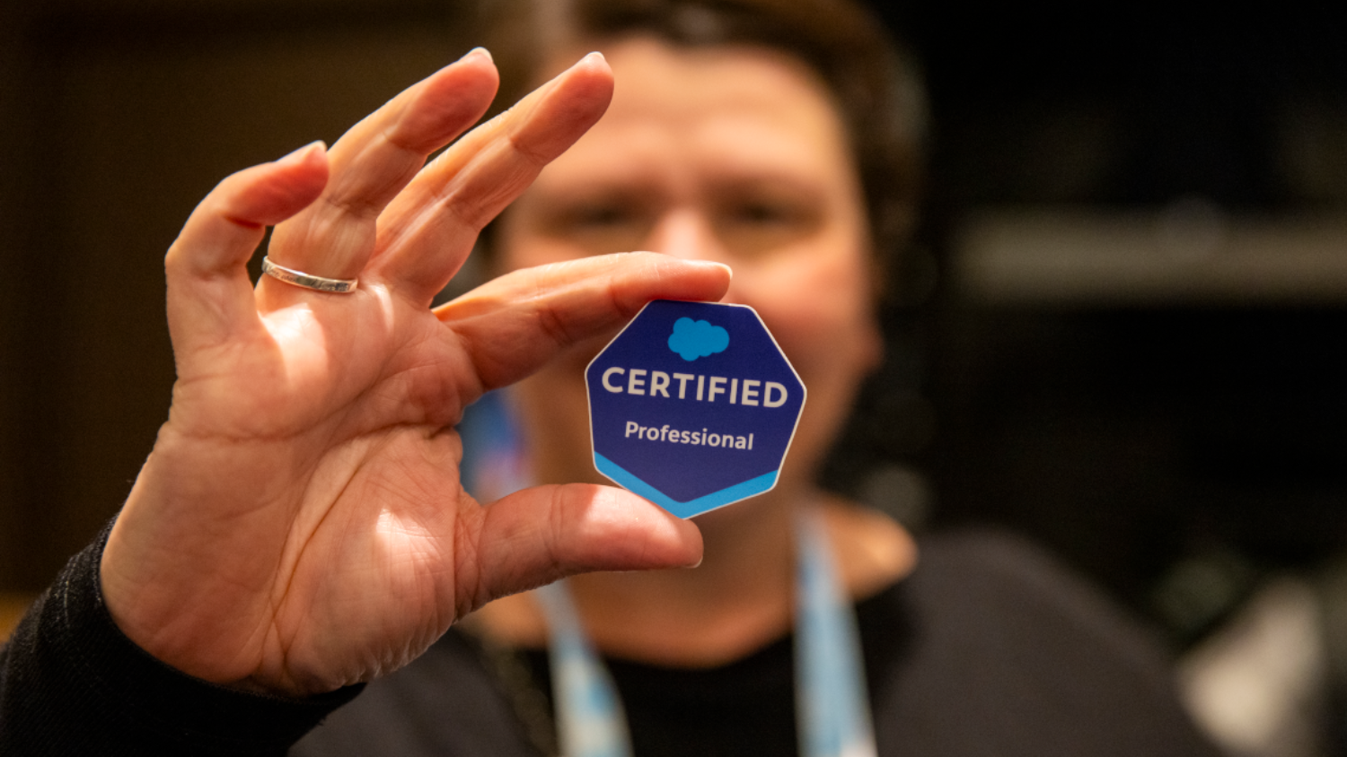 Close-up of a 'Salesforce Certified Professional' badge sticker held in a hand, representing the new AI certification in the portfolio