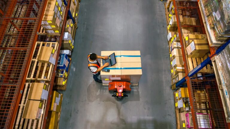 A warehouse worker using laptop to check location of goods.