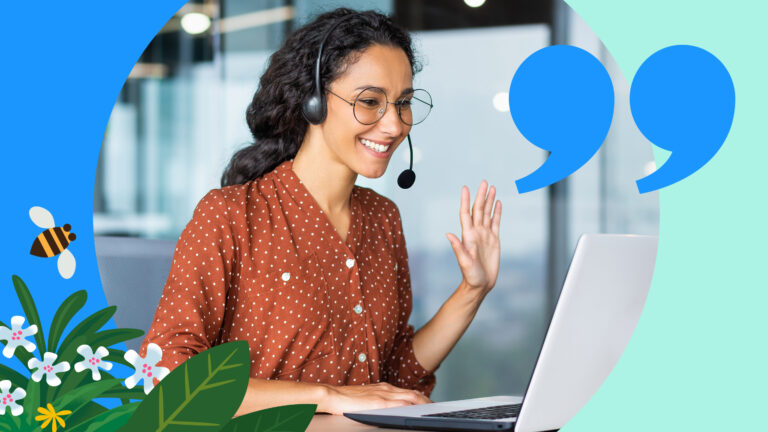 A smiling saleswoman waves while using a laptop from the deal desk.